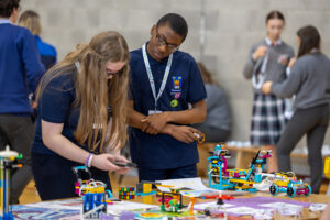 A male and female student working together at a table to prepare their LEGO robot working on their 