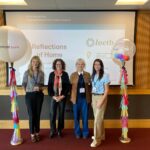 Four ladies standing in from of presentation with balloons each side of them