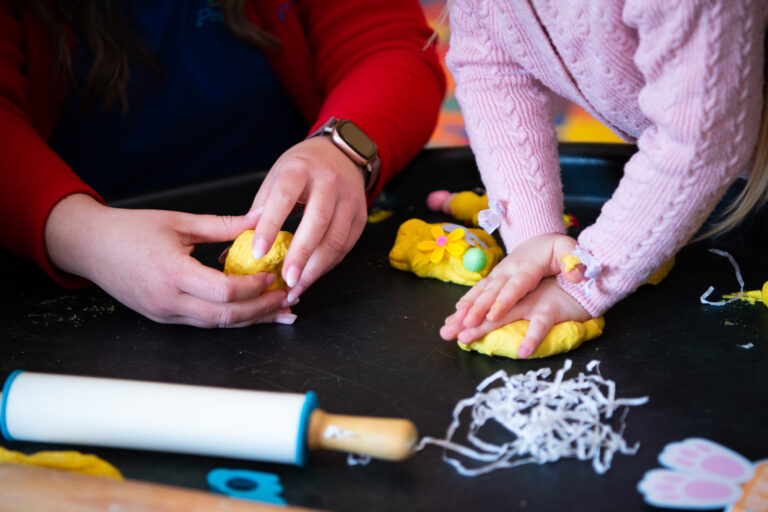 Child and adult playing with putty